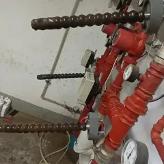 Pierwsze uruchomienie ogrzewania podłogowego. Widoczne czerwone rury, pompy i manometry.